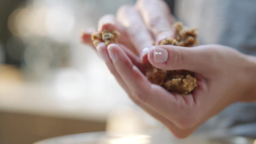 Woman takes cookie dough out of a bowl and starts to roll it into a ball