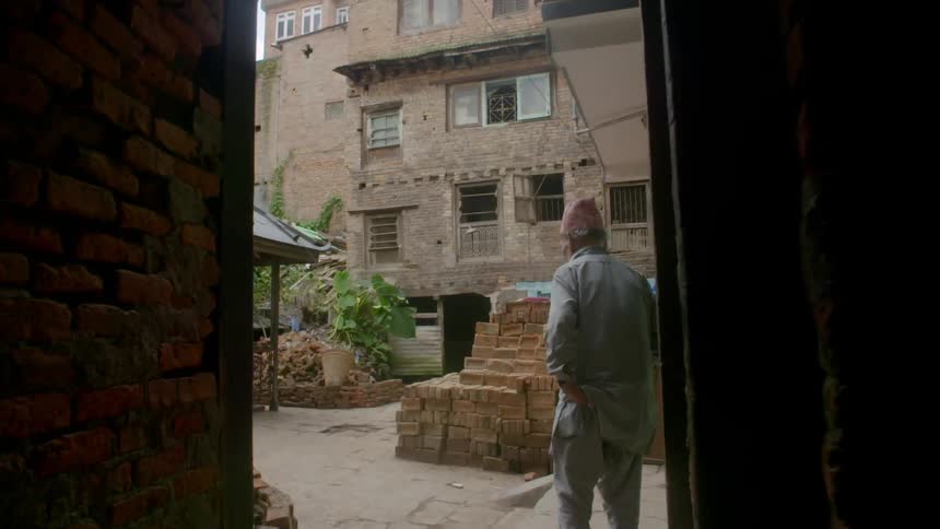 A man is standing in an alley near a building