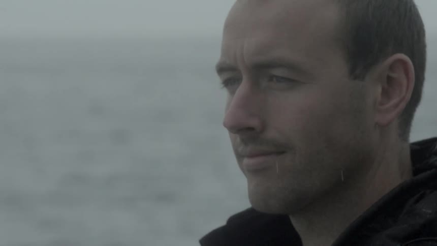 A man look out towards the ocean while it rains