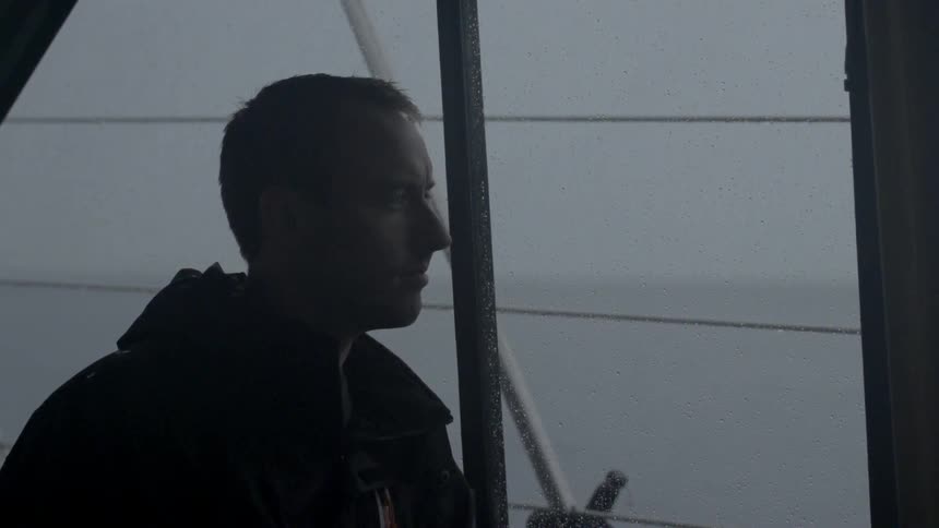 Stoic looking man looking out at some water