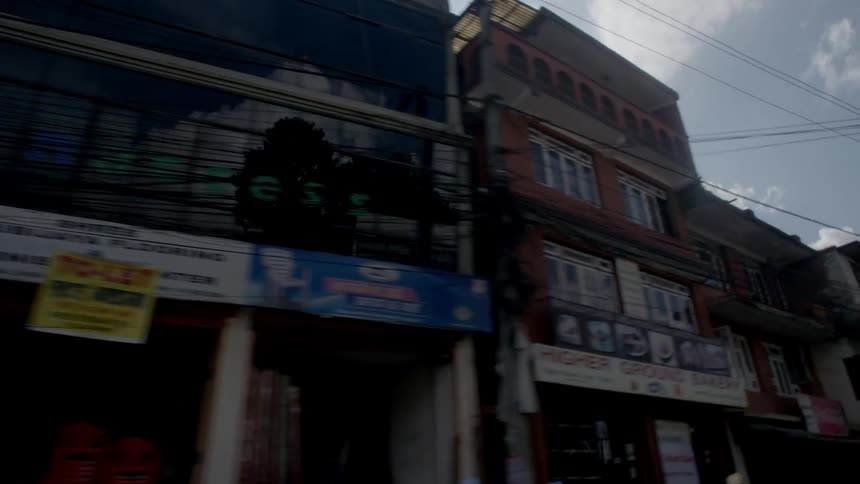 Moving past a commercial street with many buildings and stores