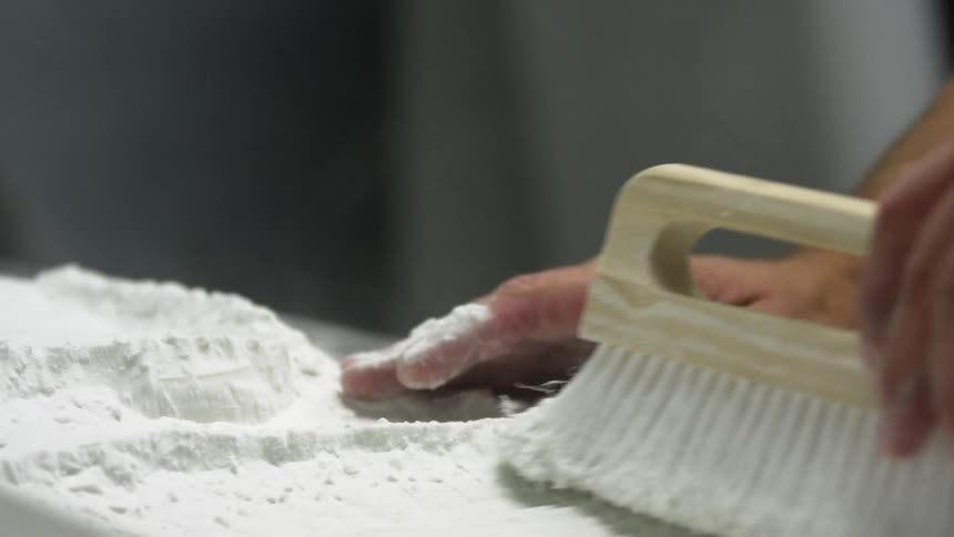 A person with a ring brushing white powder with a brush