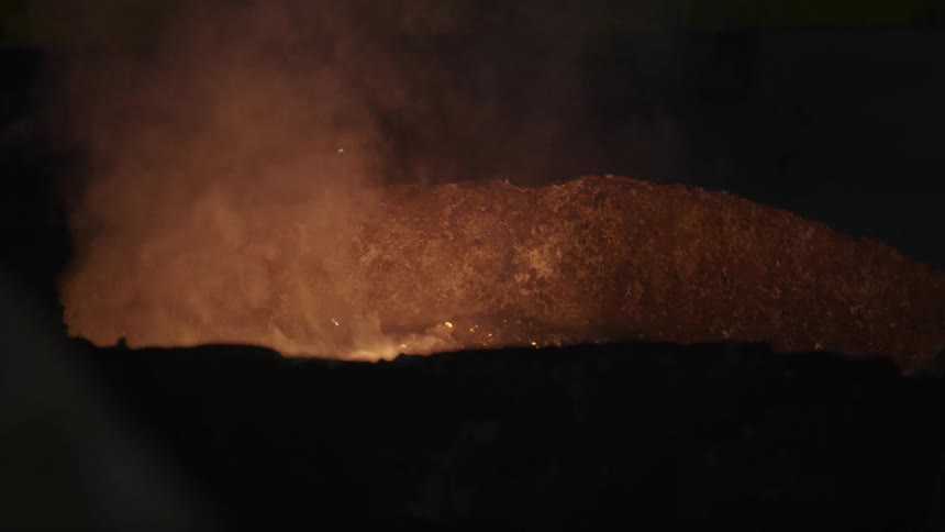 Fire is burning in pit then a ball of something burning is dropped into it creating sparks