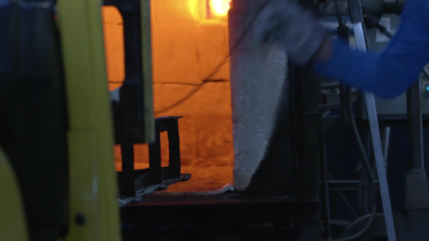 Forklift placing a pallet inside an industrial furnace in a warehouse