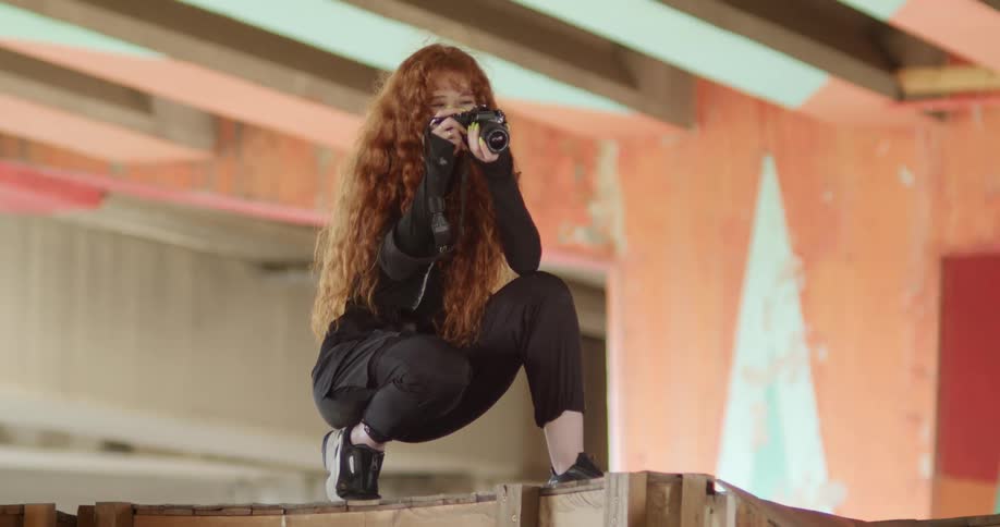 A long redhaired woman taking pictures on a stage