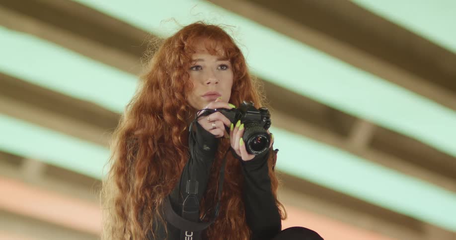 Woman with red curly hair takes a picture with a camera