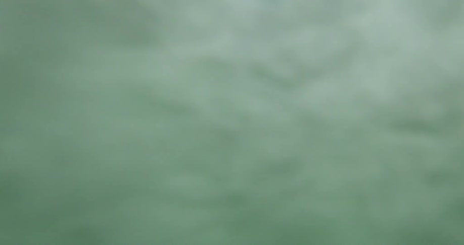 A green ocean wave crashing down on a sunny day