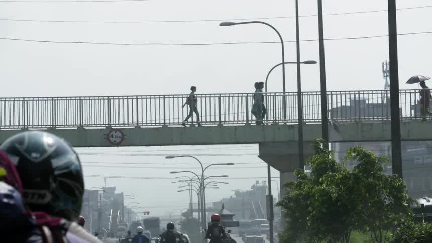 People walking and driving under a bridge
