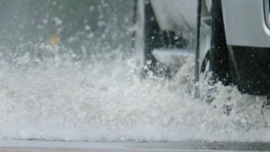 Slow motion tight shot of a white SUV driving through flooded roadways while storm chasing