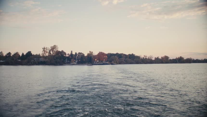 A body of water with ripples with trees the sky and clouds in the background