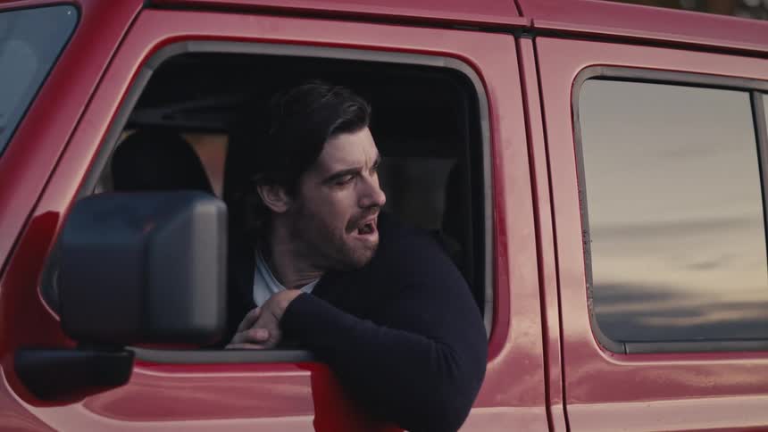 A man rolls down the window of a vehicle he is sitting in