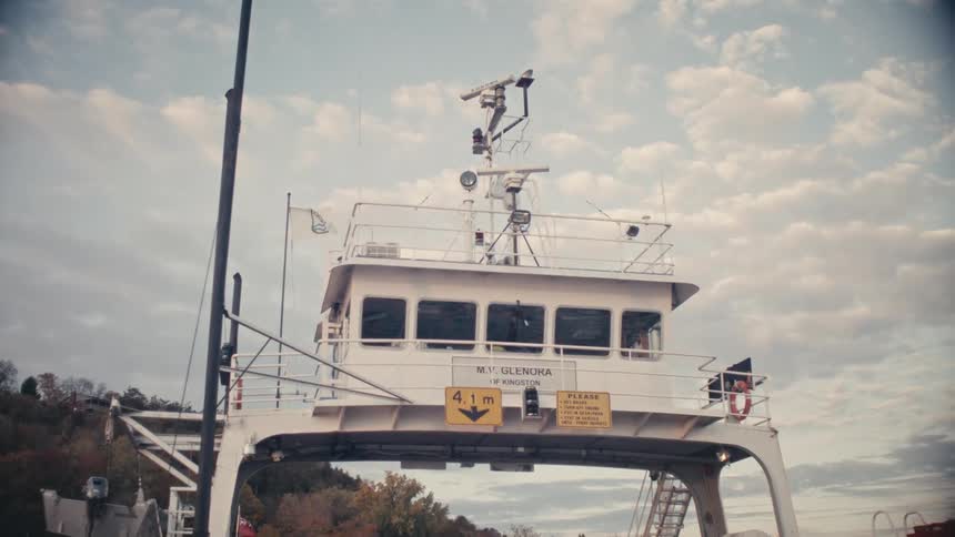 A row of vehicles parked on the deck of a ferry shuttle on a river