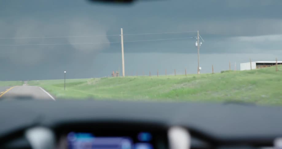 Handheld shot looking out the window at lowering and swirling storm clouds while storm chasers pursue unique and damaging weather