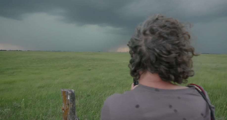 A middle aged man photographs massive bolts of lightning as a severe thunderstorm rapidly approaches while storm chasing