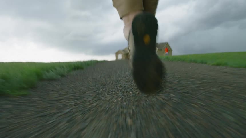Photographer man running towards a house to photograph a tornado on the ground in a shot that has intense energy and motion
