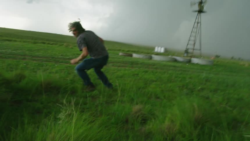 Massive hail pounds down on top of a photographer man before the danger is too intense and he runs urgently back to shelter as hail pounds the foreground
