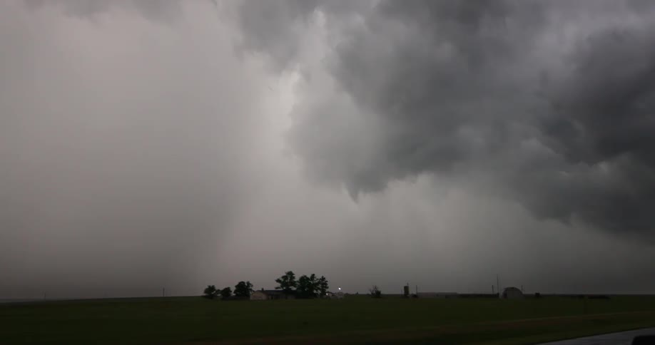Looking out the window of the moving car at a severe thunderstorm weather cloudburst with rural farmland in the foreground