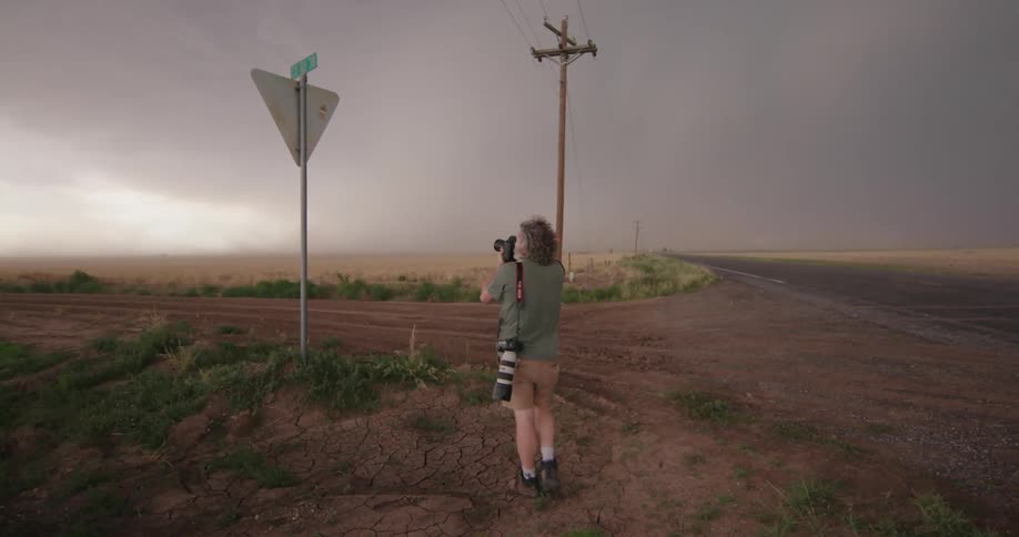 A supercell thunderstorm with outflow winds deep in Texas as a middle aged photographer takes pictures of the weather phenomena