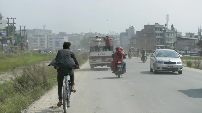 People are driving and riding bikes on a road