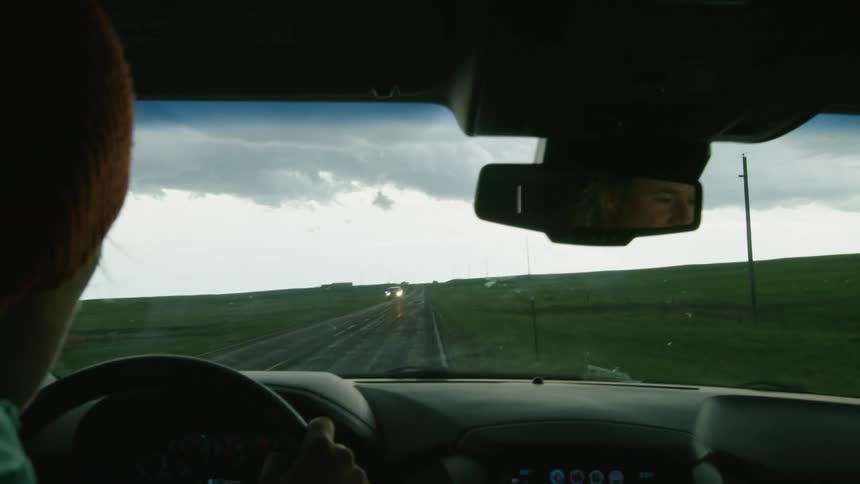Emergency vehicles rush by in the opposite way after a tornado struck a small town as seen from the perspective of a moving vehicle