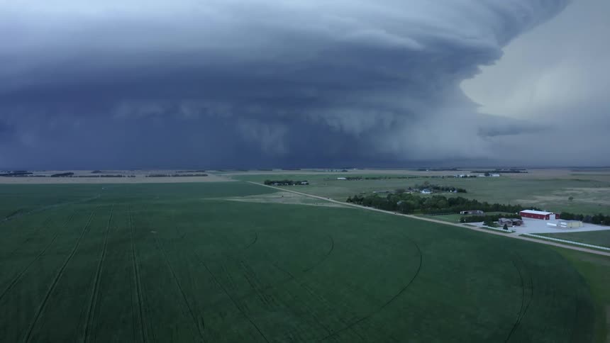 Aerial shot slowly rising above Imperial Nebraska revealing an impossibly complex and powerful severe supercell thunderstorm mothership cloud formation over rural farmland