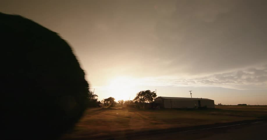 Driver POV looking out the window of a rural neighborhood and huge thunderstorm in the sky as the sun peeks out after dumping rain on the region
