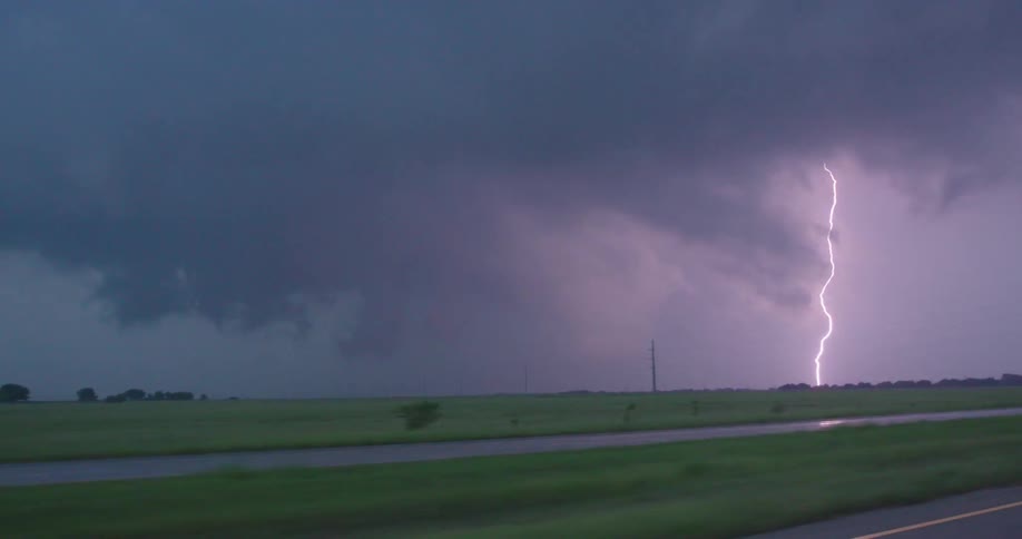 Real time shot of intense lightning bolt striking the ground from the perspective of looking out the window driver POV
