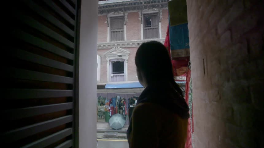 Person standing in a doorway watching the snowfall outside