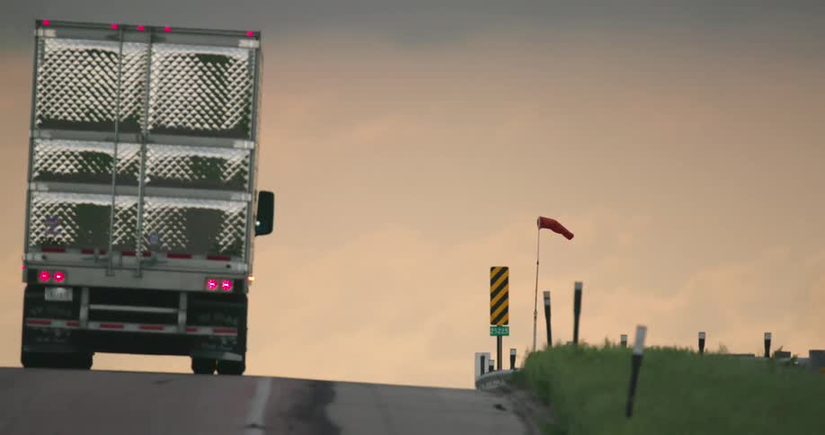 A windsock blows horizontal and a large semi drives past it as strong outflow winds blow during a super cell severe thunderstorm in Nebraska