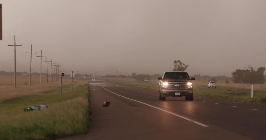 Debris is blown across the road as strong outflow winds from an approaching severe thunderstorm overwhelm the Texas panhandle during tornado season