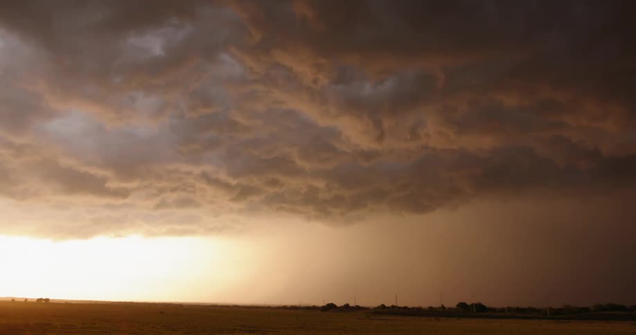 Time lapse of a severe thunderstorm passing through an open field as the storm pushes east revealing a brilliant setting sun