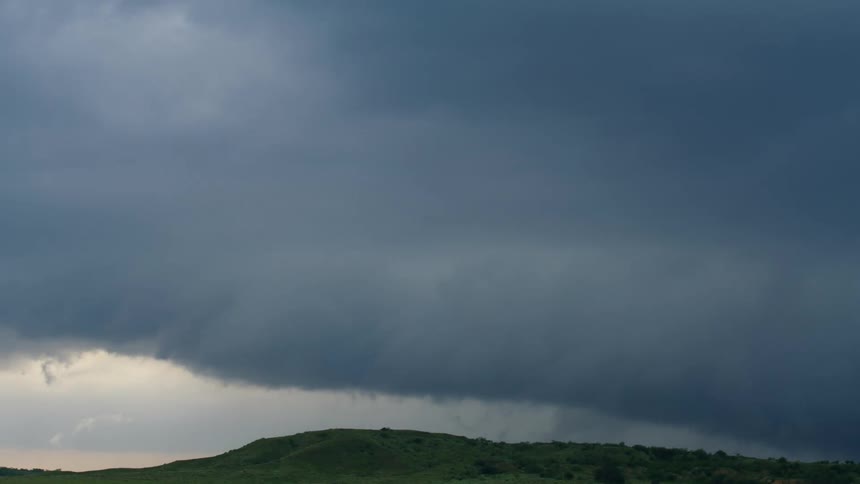 Time lapse of lowering and threatening storm clouds low on the horizon with many spin up funnel clouds dropping from the sky