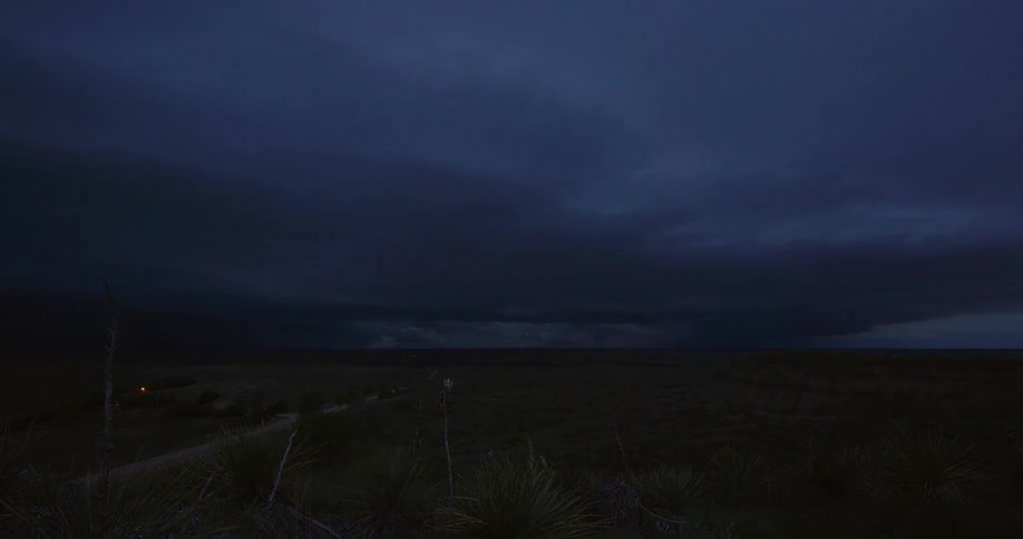 Time lapse of a severe thunderstorm spreading out across the Nebraska landscape as the sunsets and the sky turns black with yucca plants in the foreground