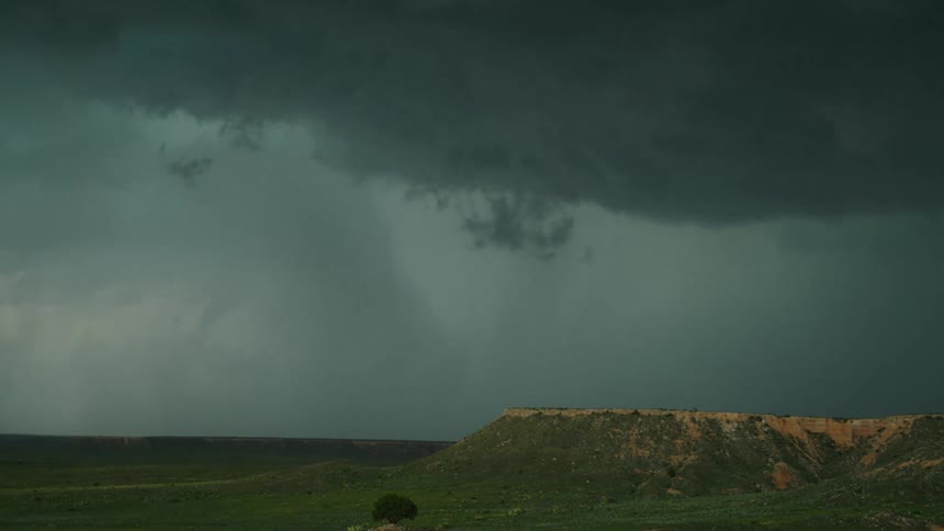 Time lapse of turquoise colored severe thunderstorm clouds swirling and building over a grassland prairie and mesa butte