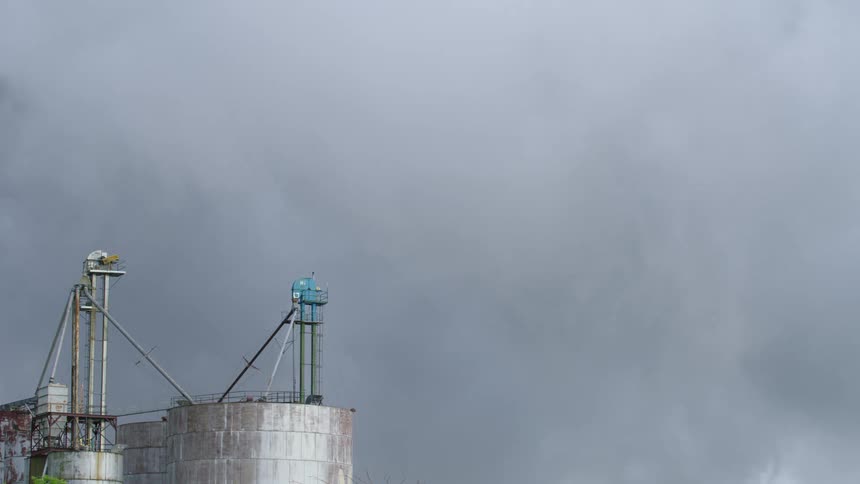 Time lapse of grain silos and severe thunderstorm clouds passing by in the far distant background