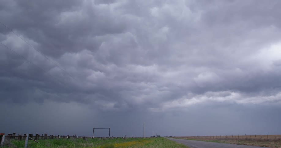 Time lapse looking down a rural road with a sky filled with rolling and tumbling storm clouds that resemble waves in the ocean
