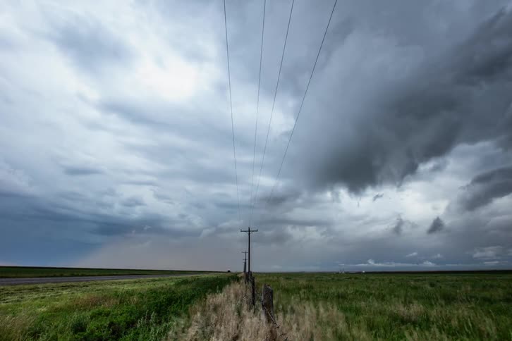 Powerlines are center framed in this time lapse as storm clouds churn and form on either side of the power lines creating symmetry and beauty from chaos