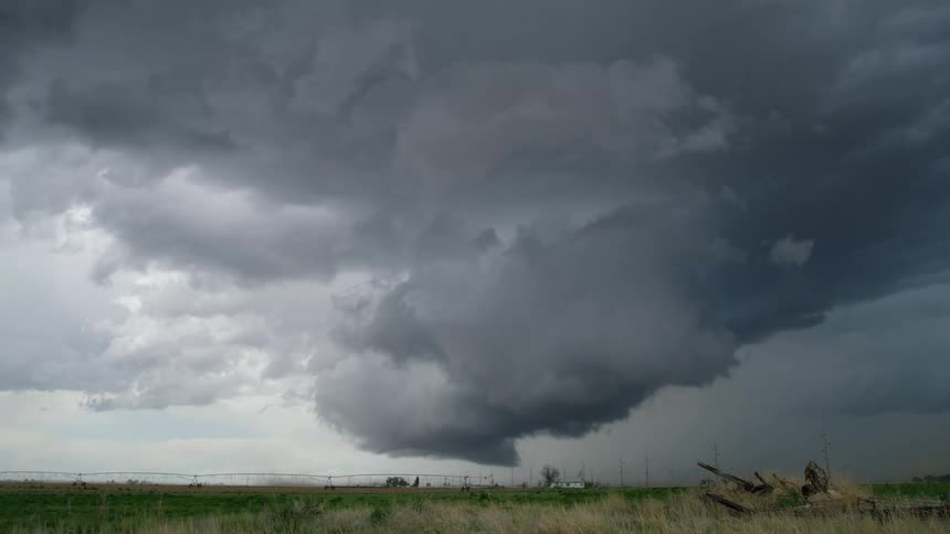 Time lapse of super cell storm capable of forming a tornado going through a field in the country as a combine tractor seeks shelter before the storm hits in eastern Colorado