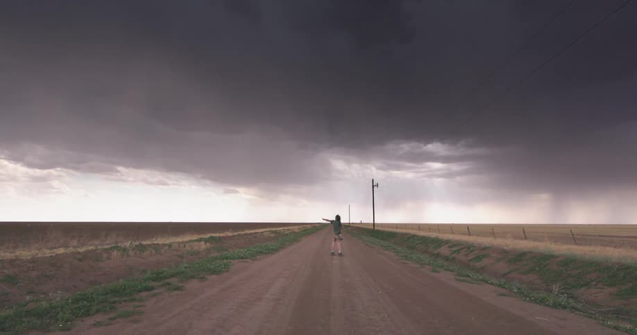 Center frame symmetrical shot of a middle age man stormchaser adventurer photographing a severe thunderstorm in rural America
