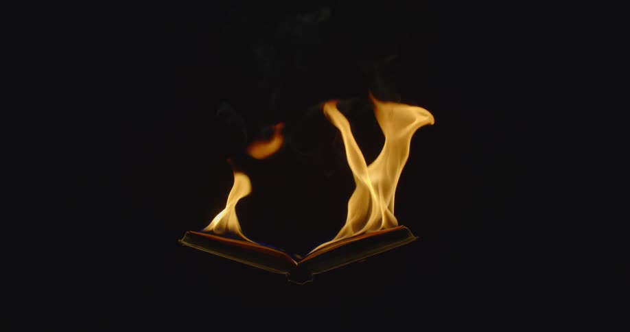 In a very dark setting an open book is on fire and theflames dance upwards