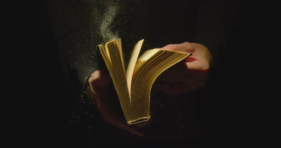 Hands holding an old book flipping through the pages as dust flies off