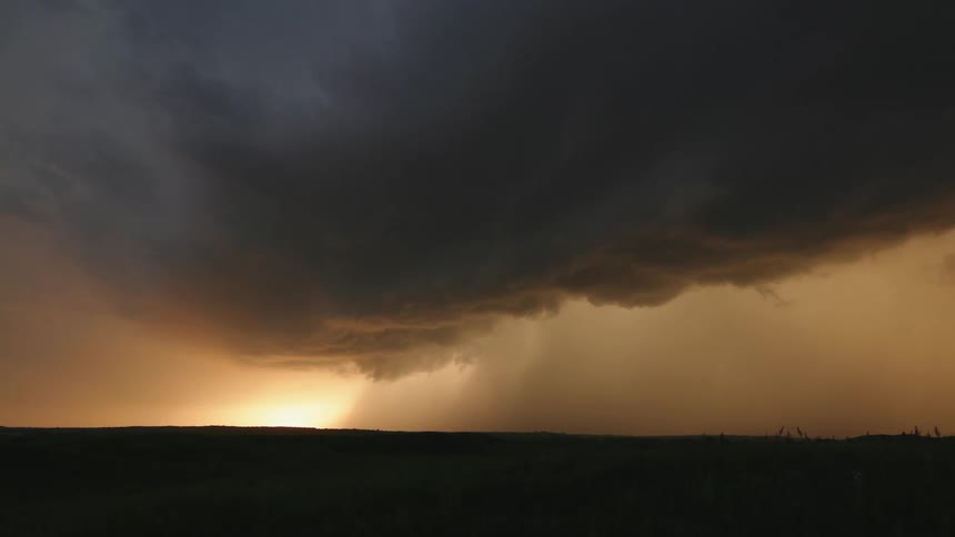 Time lapse of a severe supercell thunderstorm  at sunset with awesome contrasting purple and golden light punctuated by bolts of intense lightning