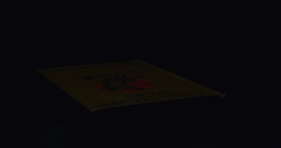 A person slams a burning book shut in the dark
