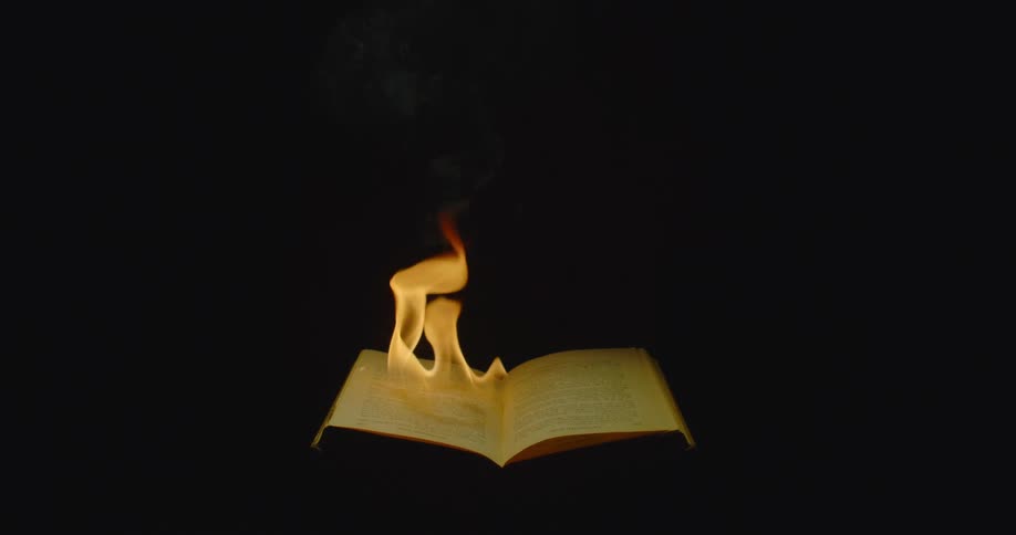 A man holds open a book that is on fire and closes it