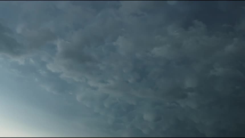 Time lapse of mammatus supercell severe thunderstorm silver and blue clouds moving left to right across the frame at sunset