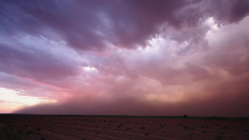 Pink and purple hued clouds fill the sky as a Haboob desert wind storm rushes towards camera in the far reaches of Texas at sunset