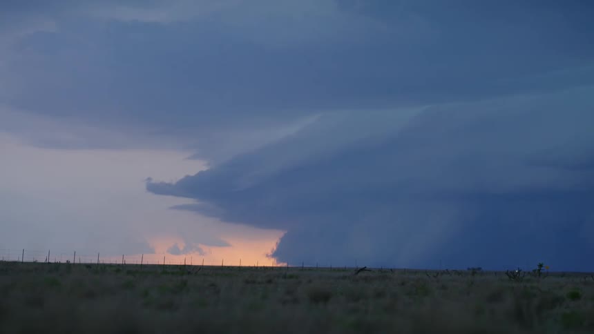 Time lapse of a massive anvil shaped severe thunderstorm roaring and pushing into the horizon in this wide shot at sunset