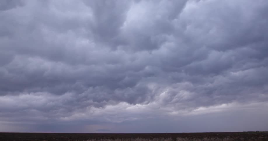 Sunset time lapse of unsettled storm clouds crashing and tumbling in the sky chaotically and with force