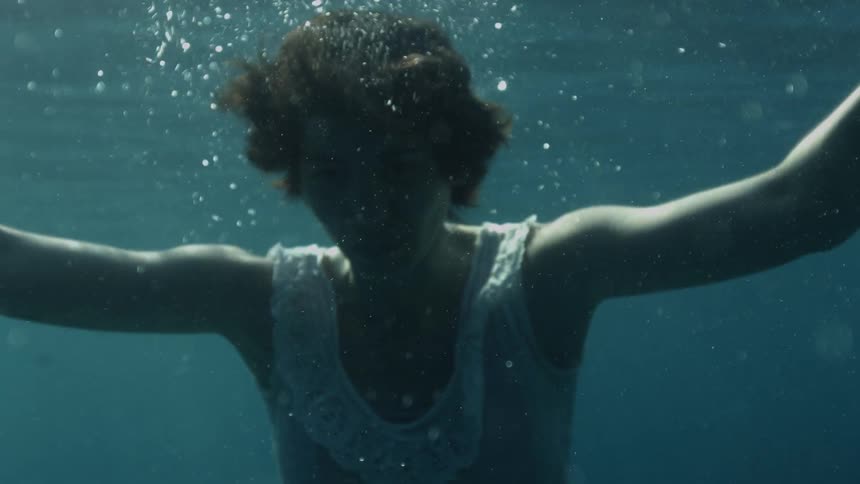 A woman goes under water and then floats to the surface