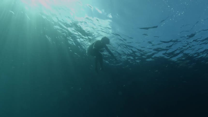 Under water shot of person floating in the water face down